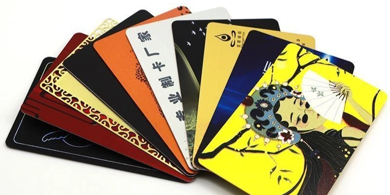 Stack of freshly printed PVC cards including hotel key cards membership cards and employee ID badges with full-color graphics on a white production table showing professional print quality Stack of freshly printed PVC cards including hotel key cards membership cards and employee ID badges with full-color graphics on a white production table showing professional print quality